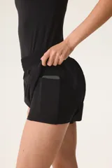 Pantalón corto deportivo negro de doble capa con cintura elástica fruncida y calzas ciclistas integradas.