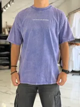 Remera oversize gris con efecto gastado, mangas cortas y estampa con texto blanco en el frente y en la espalda.