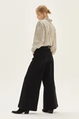 Jean de tiro alto, pierna ancha y color negro. Presenta costuras marcadas en el frente que recorren verticalmente la pierna.