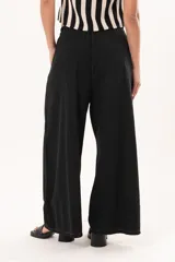 Pantalón negro de pierna súper amplia, confeccionado en denim fino y liviano con caída fluida. Tiene cintura elastizada con lazo regulable, bolsillos laterales y pinzas en la delantera.