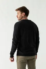 Sweater de punto color rosa con cuello en V y logo bordado en el pecho.