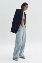Jean de pierna recta en denim de algodón rígido, con diseño de aberturas laterales en la cintura decoradas con cristales brillantes. Presenta un corte holgado, cintura con borde desflecado y bajo deshilachado.