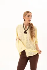 Camisa de corte oversize y mangas murciélago, confeccionada en tela con perforaciones tipo broderie. Presenta cuello mao, cierre frontal con botones y un diseño holgado y fluido.