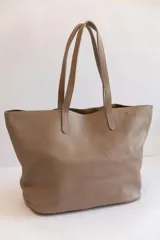 Bolso tote de cuero color tostado, con doble asa de hombro y diseño minimalista. Incluye un bolsillo separador extraíble.