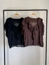 Blusa negra de algodón con escote en V y volados frontales, de mangas cortas fluidas.