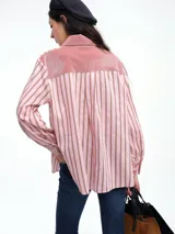 Camisa de corte relajado con estampado de rayas verticales, destacada por detalles en terciopelo en el cuello, puños y canesú. Presenta cierre frontal con botones y mangas largas.