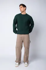 Pantalón tipo carpintero de corte relaxed fit y tiro medio, confeccionado en denim negro con costuras a contracolor en blanco. Presenta múltiples bolsillos cargo laterales, un bolsillo con cierre en la parte inferior y presillas utilitarias.