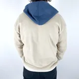 Canguro tostado con capucha azul marino, cierre parcial con cremallera, bolsillo tipo canguro y logo bordado en azul.