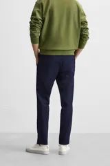 Pantalón de corte slim fit confeccionado en tejido elástico, con cintura elástica, cierre frontal con cremallera y botón, bolsillos laterales y bolsillos traseros de vivo.