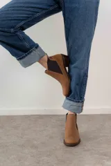 Bota corta de cuero color marrón con elásticos laterales, taco bajo y punta redondeada.