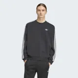Buzo Adidas de cuello redondo con corte oversize, confeccionado en tejido de punto. Presenta las icónicas tres franjas blancas en las mangas y el logo del trifolio bordado en el pecho.