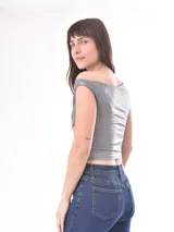 Musculosa plateada de corte asimétrico con escote bote caído que deja un hombro al descubierto, confeccionada en tejido elástico con acabado metalizado.