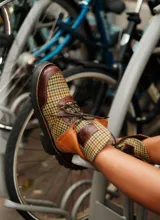 Botas de caña baja con base de terciopelo y paños de tweed a cuadros en tonos marrones, beige y verde. Presentan detalles en cuero marrón y cordones marrones.