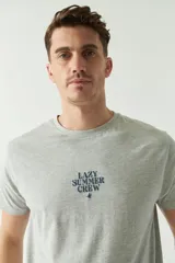 Remera gris de hombre con cuello redondo, manga corta y estampado en el pecho con la frase "Lazy Summer Crew".