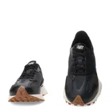 Championes New Balance modelo 327, color negro con logo "N" en cuero sintético negro, entresuela blanca y suela de goma marrón.