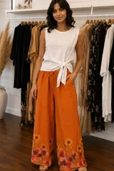 Pantalón amplio color naranja, de corte holgado, con cintura elastizada y cordón ajustable. Presenta un estampado de flores botánicas en la parte inferior.
