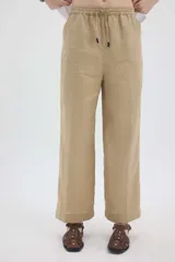 Pantalón de lino color beige, de silueta relajada, tiro medio-alto, cintura elastizada con cordón ajustable, bolsillos laterales y bolsillos traseros.