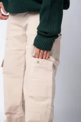 Pantalón tipo carpintero de corte relaxed fit y tiro medio, confeccionado en denim negro con costuras a contracolor en blanco. Presenta múltiples bolsillos cargo laterales, un bolsillo con cierre en la parte inferior y presillas utilitarias.