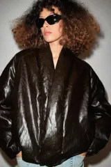 Cazadora acolchada Zara de efecto piel en color negro, con cuello en pico, manga larga, bolsillos delanteros y cierre frontal cruzado con botón.