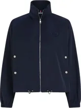 Cortavientos azul marino con cuello alto, cierre de cremallera, dos bolsillos con botones, detalles distintivos de Tommy Hilfiger y logo gráfico bordado en el pecho.