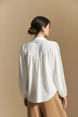 Camisa de manga larga con caída fluida, diseño de silueta suelta, cuello clásico y cierre frontal con botones.