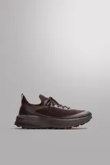 Zapatilla deportiva de correr para trail running, color marrón oscuro. Presenta una parte superior de tejido de punto transpirable, puntera y talón reforzados con material Shield Protect Max. Cuenta con ajuste de cordones, tirador trasero, plantilla OrthoLite® extraíble, entresuela Spume Foam V2 y suela de goma.