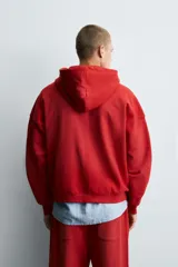 Sudadera roja con capucha, cierre frontal con cremallera, bolsillos tipo canguro y corte relaxed boxy fit.
