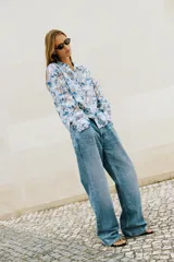 Camisa de manga larga con cuello solapa y cierre frontal de botones, confeccionada en tejido combinado semitransparente con estampado floral en tonos azules y blancos.