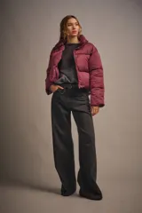 Campera puffer corta color borgoña, de corte holgado y cuello alto con cierre y snaps escondidos.