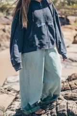 Pantalon de denim estilo wide leg en color verde lavado, con corte holgado y diseño de tiro medio. Presenta costuras reforzadas y detalle de marca bordado verticalmente en la pierna.