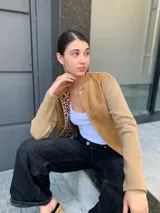 Campera marrón con cuerpo de cuero y mangas de lana color beige. Interior con estampado animal print. Corte clásico con cuello redondo y cierre frontal con botones a presión.