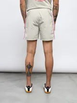 Short de baño negro con una banda vertical blanca en el lateral con el logo de Umbro en color rosa.