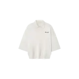 Remera polo de punto de Fear of God Essentials, color gris claro, de manga tres cuartos y corte oversize estilo años 90. Presenta cuello camisero con cierre frontal de un botón y el logo bordado en el pecho.
