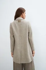 Saco corto entallado de lana fina, con cuello solapa, manga larga y cierre frontal con botones. Presenta un diseño clásico con textura de espiga en tonos tierra.