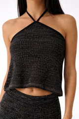 Top negro de punto con lurex dorado, escote halter y tiras cruzadas en la espalda.