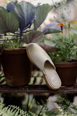 Mules de cuero negro con tachas plateadas en el borde de la suela y plantilla con logo estampado.