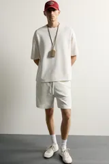 Bermuda estilo jogger de ajuste relajado, confeccionada en tejido interlock de algodón. Cuenta con cintura elástica ajustable con cordón, bolsillos frontales de vivo y diseño liso.