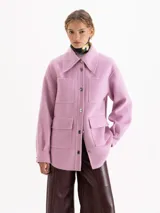 Chaqueta de paño color rosa, con cuello camisero, cierre frontal con botones metálicos y cuatro bolsillos plaqué delanteros. Presenta mangas largas y costuras con pespuntes decorativos al tono.