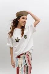 Remera de algodón blanca, de corte oversize, con mangas cortas y dos aplicaciones de flores bordadas en el frente.