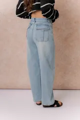Jean wide leg de tiro alto en denim color celeste claro. Presenta un diseño de cinco bolsillos, destacándose los bolsillos traseros con solapa y detalle de marca metálica. Posee cierre frontal con botón y ruedo recto.