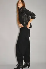 Jean de tiro medio-alto, color negro, de calce holgado con piernas anchas que se estrechan hacia el tobillo. Presenta pinzas en la zona de las rodillas que acentúan su forma 'balloon' y un recorte lateral. Confeccionado en denim rígido con lavado suavizado, cierre y botón.