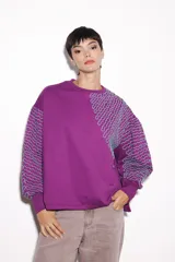 Buzo violeta de jogging con friza, corte holgado y mangas balloon. Tiene un estampado bordado con lurex.