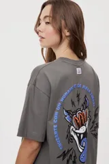 Remera de manga corta con calce oversized y cuello redondo, color gris oscuro, con pequeño gráfico de rayos naranjas en el frente.