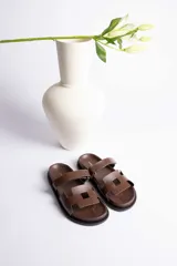 Sandalias marrones con dos tiras anchas sobre el empeine, una de ellas ajustable con hebilla dorada.