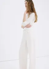 Jeans blancos de tiro medio con diseño wide leg y bordado de flores tono sobre tono en las perneras. Cuentan con diseño clásico de cinco bolsillos, trabillas y cierre frontal de botón y cremallera.