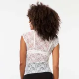 Camiseta blanca de encaje con calados, sin mangas y cuello redondo.