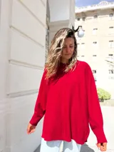 Sweater de punto color bordó, con diseño oversize, cuello redondo, mangas largas con puños acanalados y costura central vertical. Presenta un corte asimétrico con aberturas laterales en el ruedo.