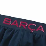 Short de fútbol azul con cordón de ajuste en la cintura, escudo del FC Barcelona en la pierna derecha y la palabra "Barça" en la pierna izquierda.