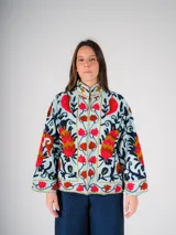 Chaqueta corta de color celeste con bordados florales en tonos rojos, naranjas, azules y negros.