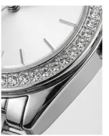 Reloj de pulsera analógico para mujer con caja de metal plateado, bisel decorado con cristales y malla de acero inoxidable. Esfera con fondo nacarado y marcadores de hora con cristales.